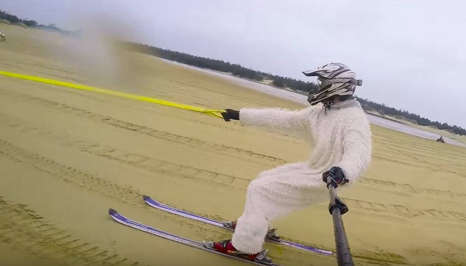 Skiing on Sand as a Yeti Tracked by a Quad Bike